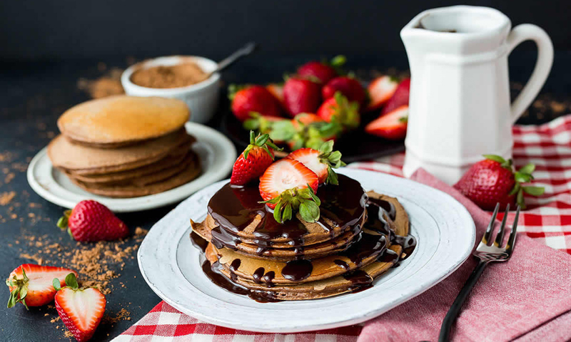 Two plates with pancakes and chocolate sauce