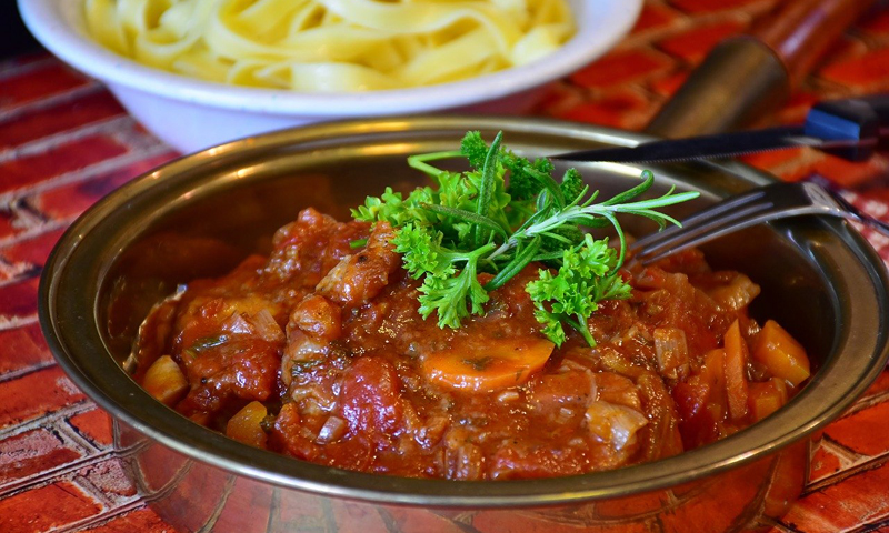 A plate with meat cooked in tomato sauce and mushrooms