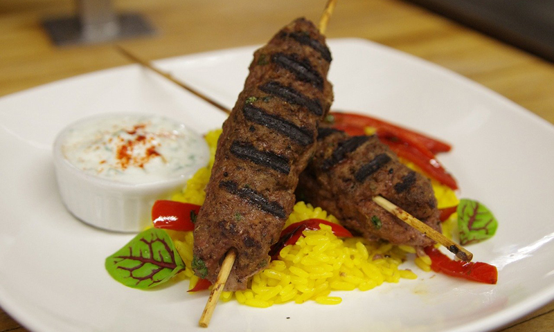 A plate with two meat kebabs and rice